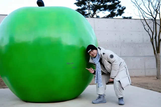A playful pose beside a giant green apple sculpture